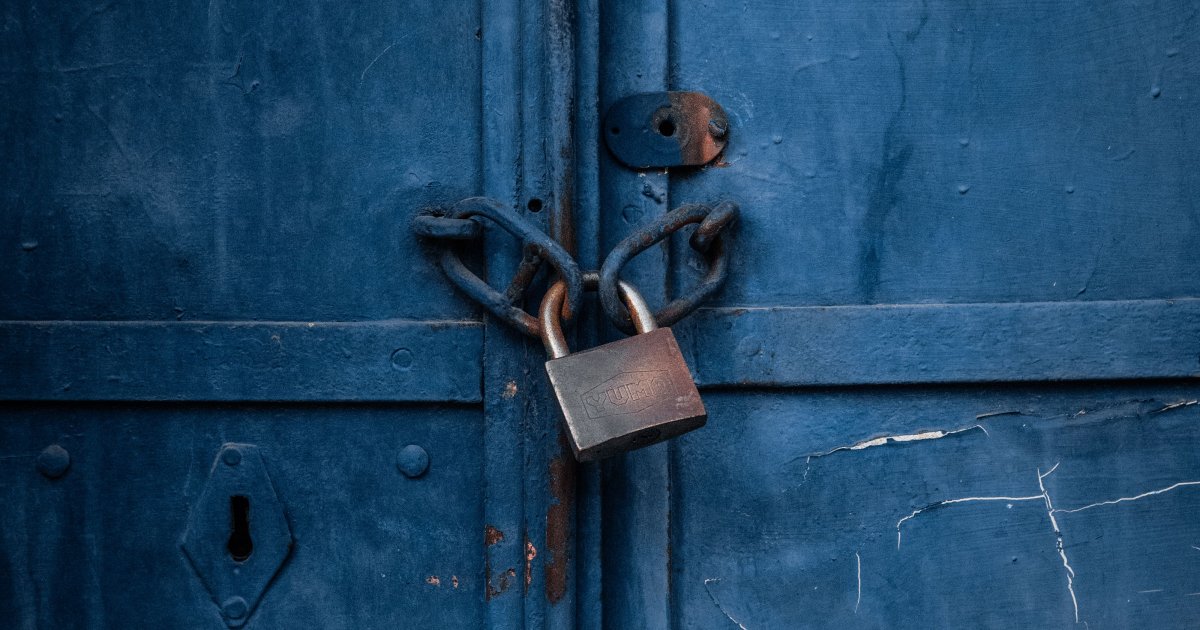 A photo of a rusted padlock holding two metal doors together. 
